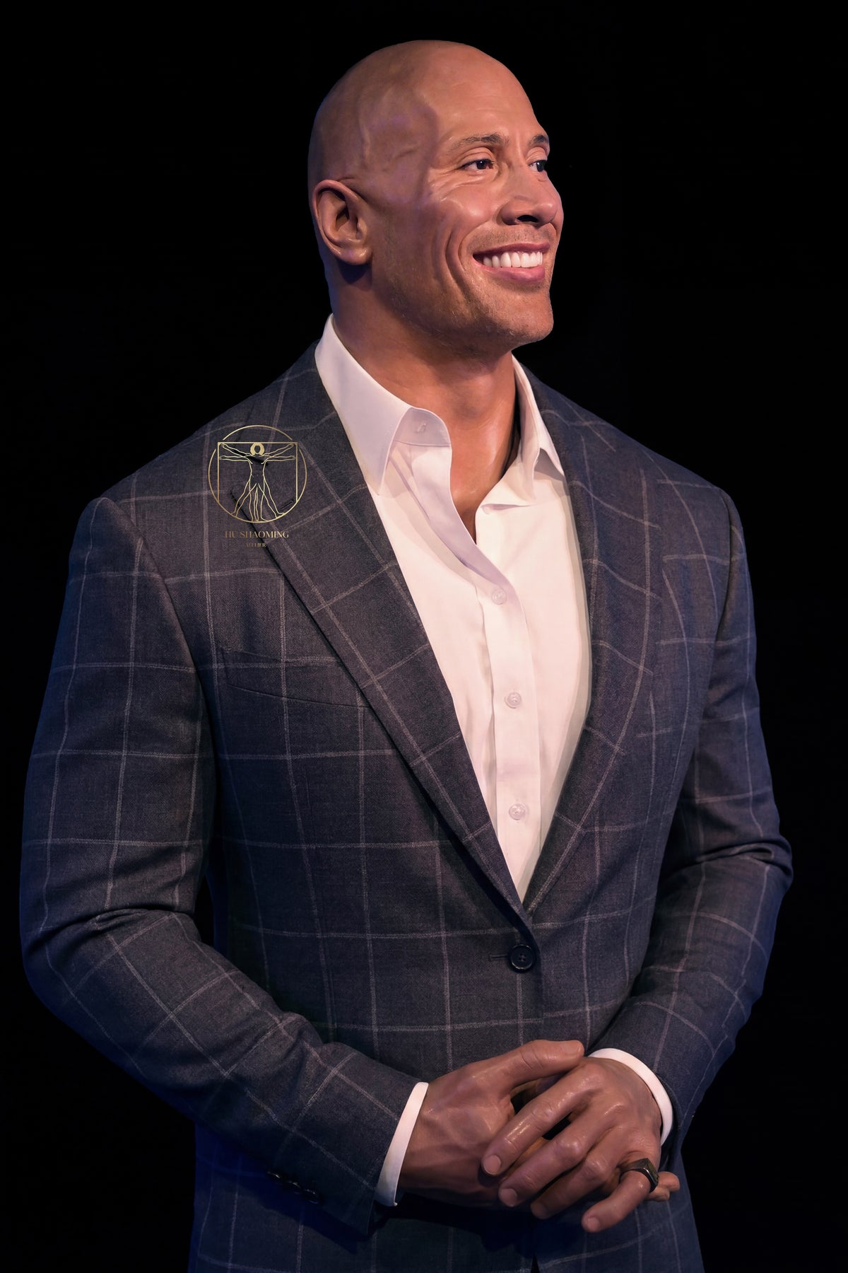 Half body silicone figure of Dwayne "The Rock" Johnson wearing a suit with clasped hands